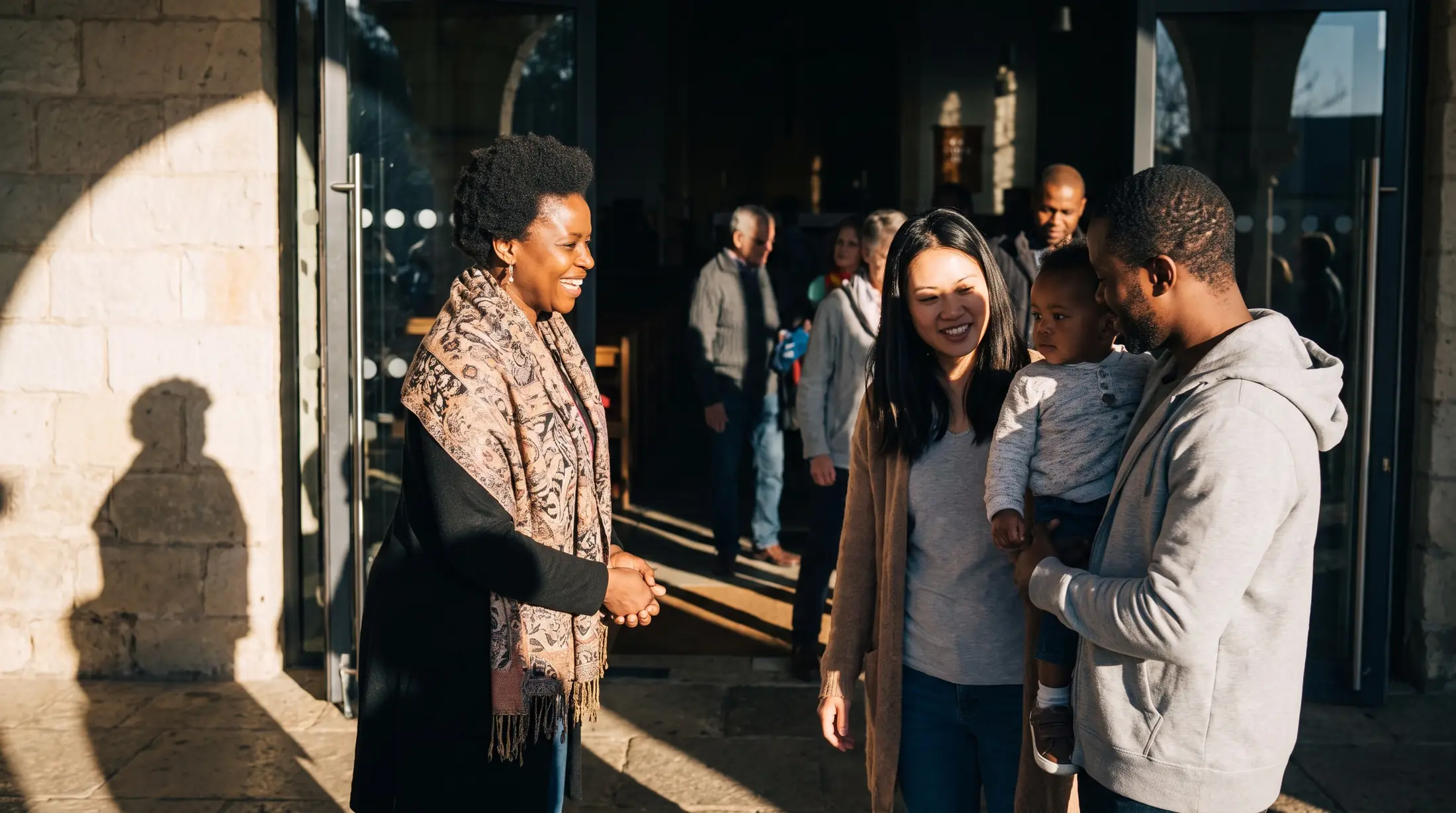 A greeter welcomes a young family at the church door